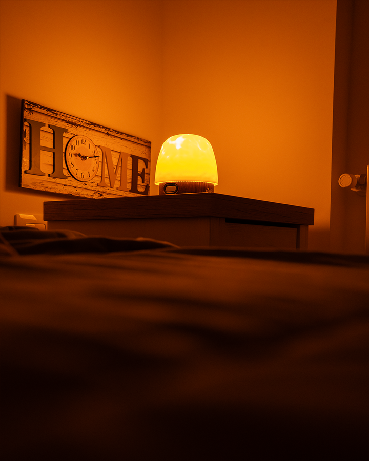 Havie diffuse une lumière jaune chaude sur une table de chevet, dans une chambre douillette