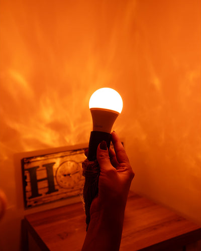 Une main tient une lampe allumée devant un mur baigné de lumière chaude