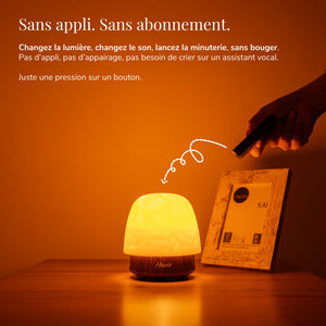 Havie se commande à la télécommande et diffuse une lueur orange chaleureuse sur une table de chevet.